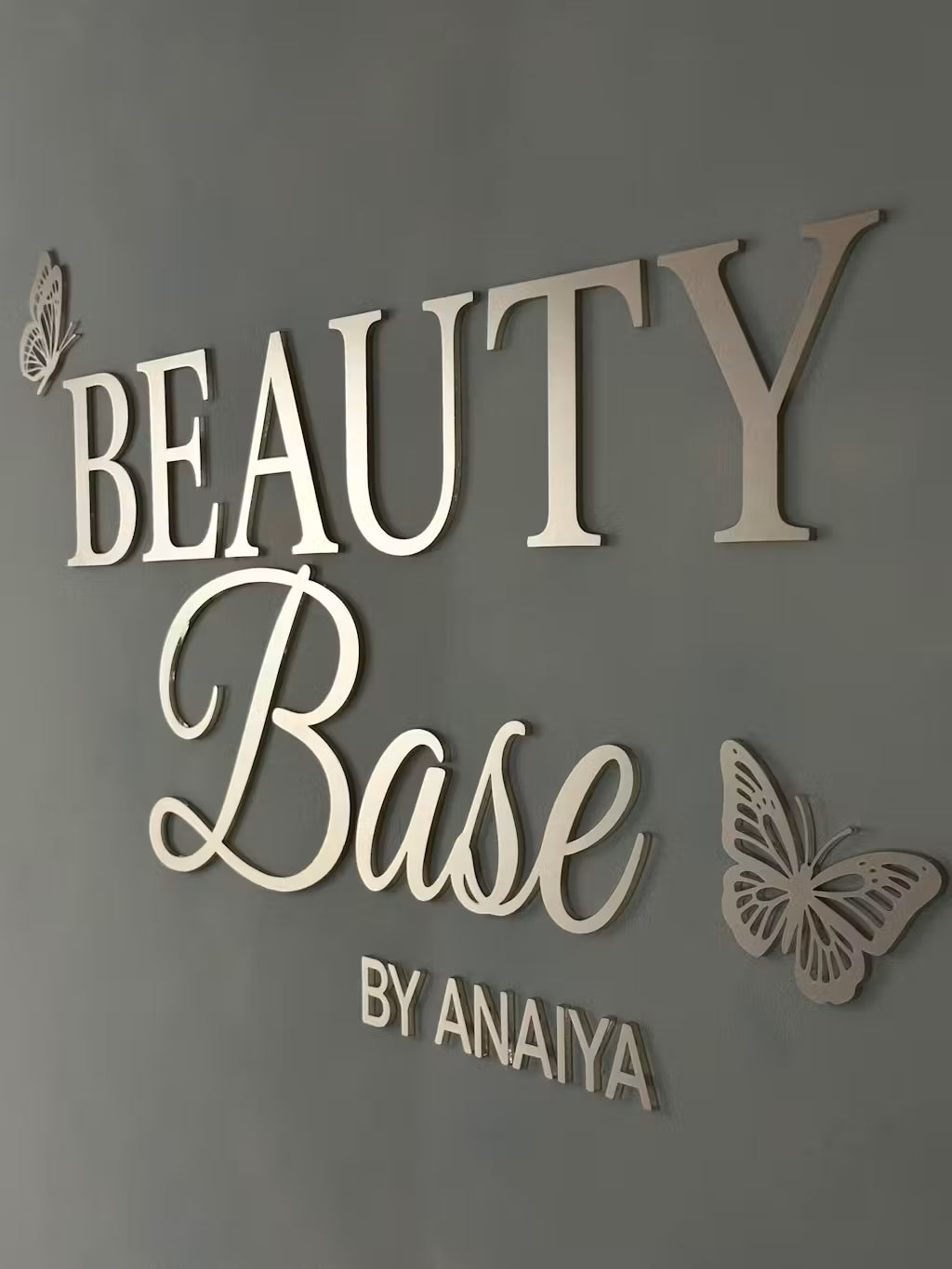 Insegna con logo personalizzato in 3D “beauty base” su una parete grigia
